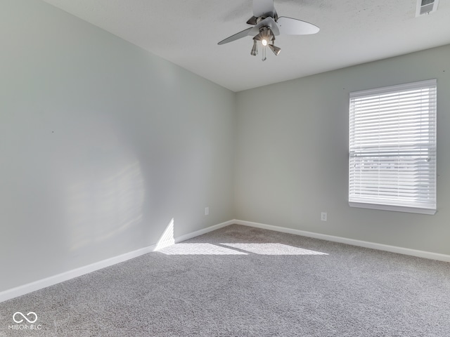 carpeted empty room featuring visible vents, baseboards, and ceiling fan