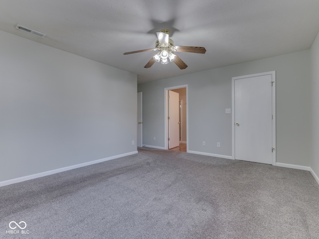 spare room with visible vents, ceiling fan, carpet, and baseboards