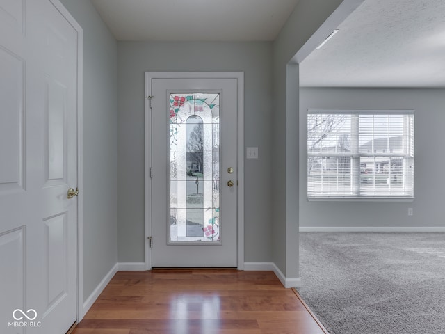 entryway featuring baseboards, carpet floors, and wood finished floors