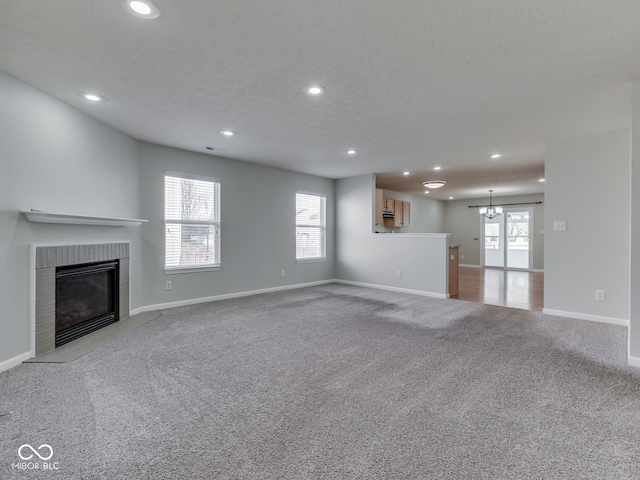 unfurnished living room with a textured ceiling, recessed lighting, carpet flooring, baseboards, and a brick fireplace