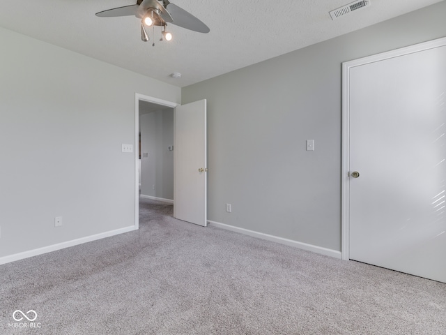 unfurnished bedroom featuring visible vents, a ceiling fan, a textured ceiling, carpet floors, and baseboards