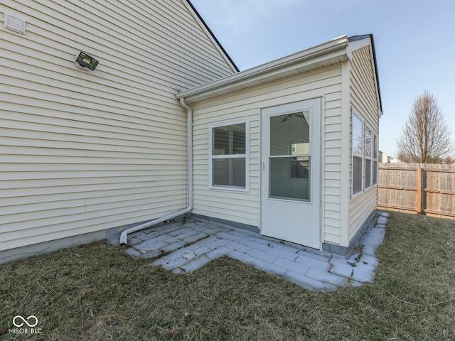 view of exterior entry featuring a patio area and fence