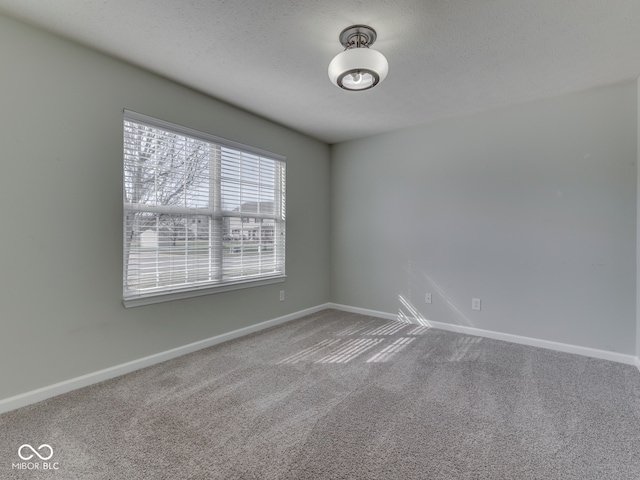 carpeted empty room with a textured ceiling and baseboards