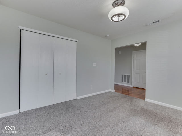 unfurnished bedroom with a closet, visible vents, baseboards, and carpet floors