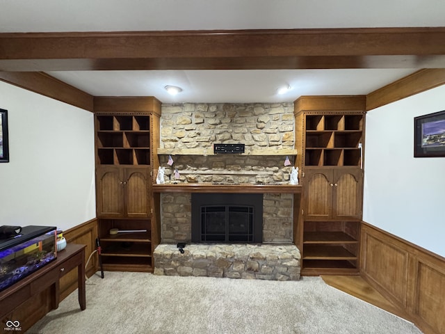 living room featuring beamed ceiling, a fireplace, and wainscoting