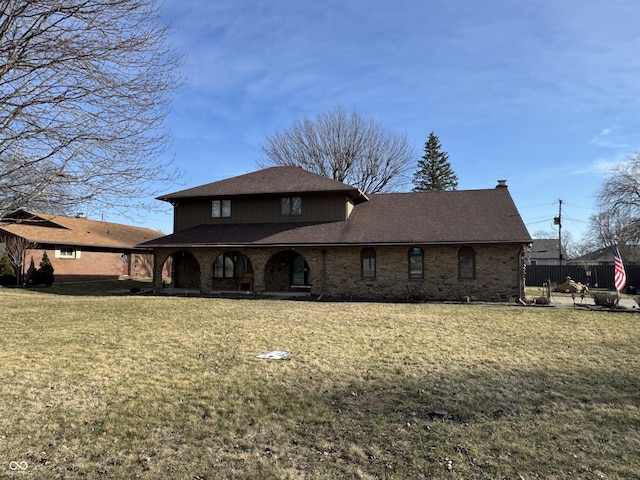 rear view of property featuring a lawn, brick siding, and a shingled roof