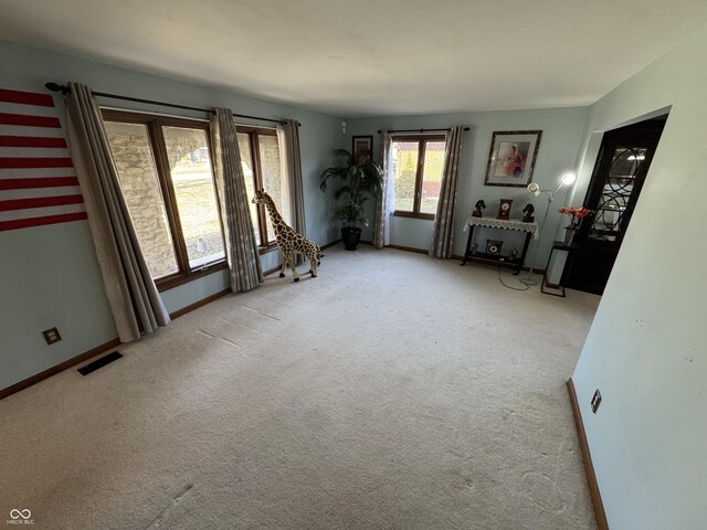 unfurnished room featuring light colored carpet, visible vents, and baseboards