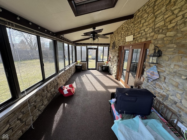 unfurnished sunroom featuring a ceiling fan and vaulted ceiling with beams