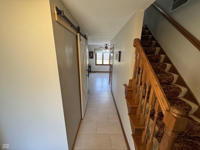 hallway featuring visible vents, a barn door, light tile patterned flooring, baseboards, and stairs