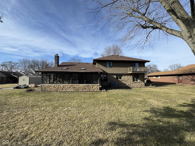 rear view of house with a balcony, a yard, a sunroom, and a chimney