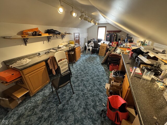 interior space with lofted ceiling, track lighting, and dark carpet