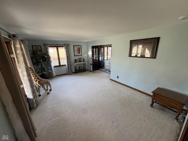 unfurnished living room featuring light colored carpet and baseboards