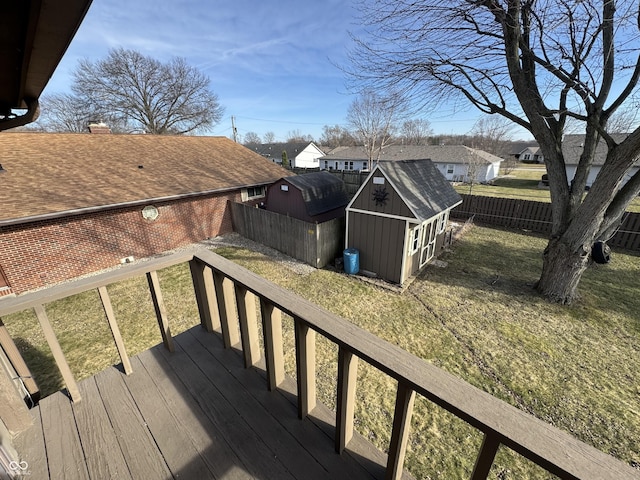 wooden terrace with a fenced backyard, an outdoor structure, a storage shed, a lawn, and a residential view