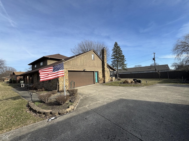 view of home's exterior with stone siding, driveway, a chimney, and an attached garage