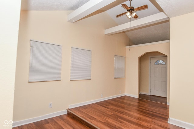 unfurnished room featuring lofted ceiling with beams, wood finished floors, arched walkways, baseboards, and ceiling fan