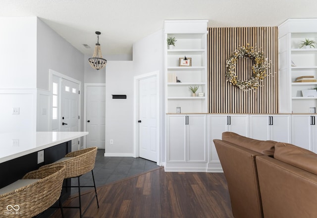 kitchen featuring built in shelves, dark wood-style flooring, hanging light fixtures, light countertops, and a kitchen breakfast bar