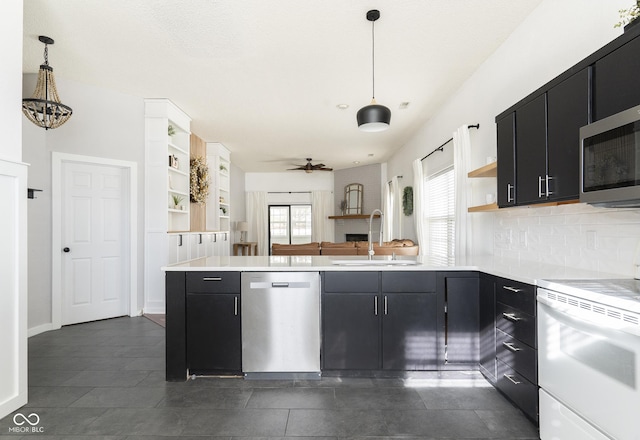 kitchen with a sink, open shelves, a peninsula, appliances with stainless steel finishes, and dark cabinets