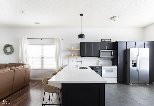 kitchen with a sink, light countertops, appliances with stainless steel finishes, pendant lighting, and a kitchen breakfast bar