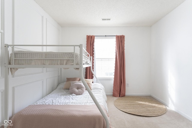 bedroom featuring visible vents, baseboards, carpet, and a textured ceiling