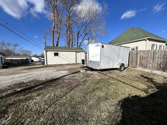 rear view of house featuring a storage unit, an outdoor structure, and fence