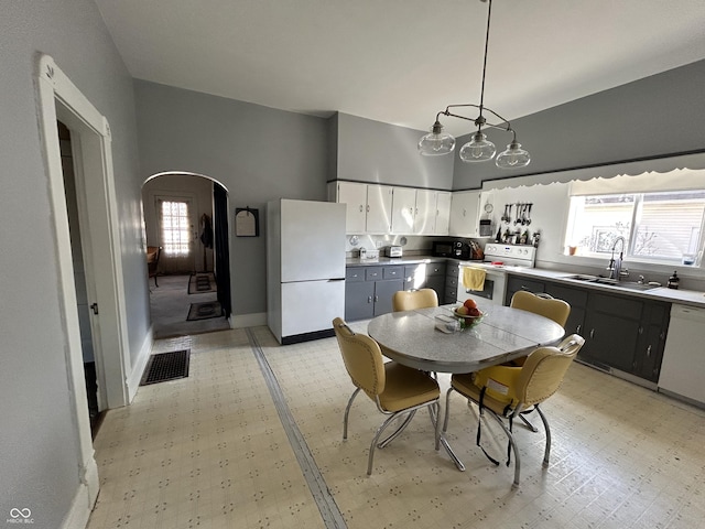 kitchen with arched walkways, light floors, white appliances, and a sink