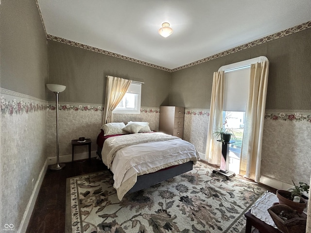 bedroom with a wainscoted wall, wallpapered walls, and baseboards