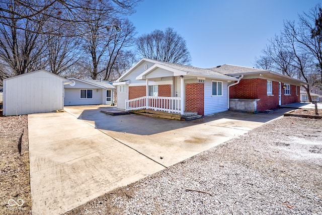 view of front of house with brick siding, a porch, and driveway