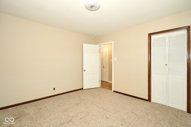 unfurnished bedroom featuring baseboards, light carpet, and a closet