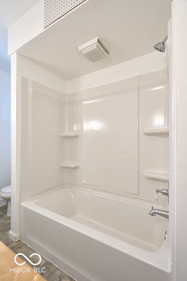 full bathroom with shower / bath combination, toilet, and wood finished floors