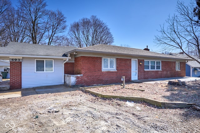 single story home with brick siding, a chimney, and a patio