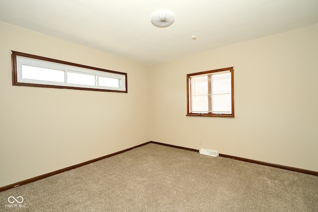 unfurnished room with light colored carpet, visible vents, and baseboards