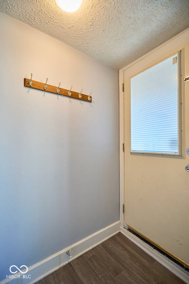 unfurnished room featuring dark wood-type flooring, baseboards, and a textured ceiling