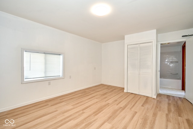 unfurnished bedroom featuring baseboards, a closet, and light wood finished floors