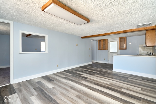 unfurnished living room with dark wood finished floors, baseboards, visible vents, and a textured ceiling