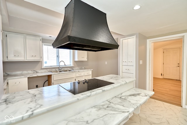 kitchen featuring range hood, a sink, white cabinetry, black electric cooktop, and marble finish floor