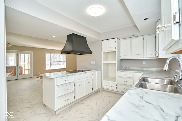 kitchen featuring a peninsula, a sink, extractor fan, white cabinets, and marble finish floor