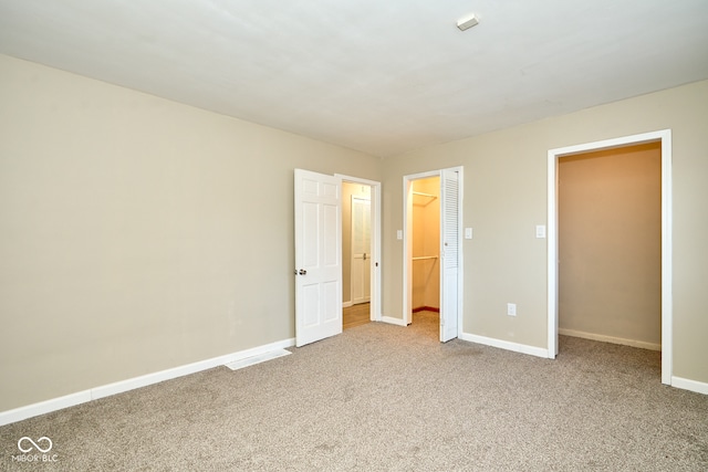 unfurnished bedroom featuring a closet, baseboards, carpet, and a spacious closet