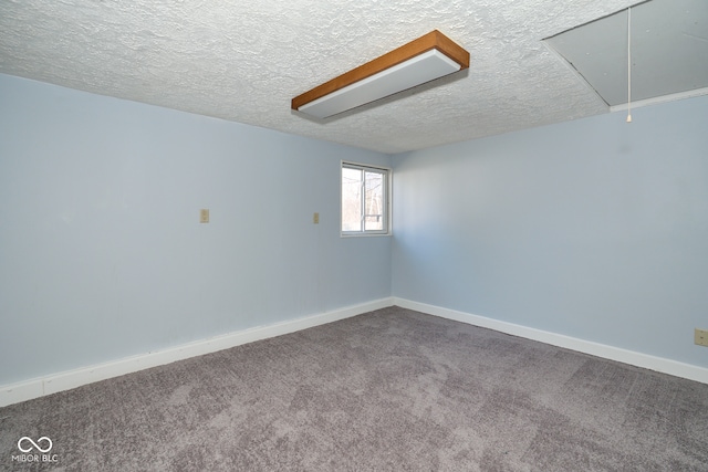 unfurnished room featuring attic access, carpet flooring, baseboards, and a textured ceiling