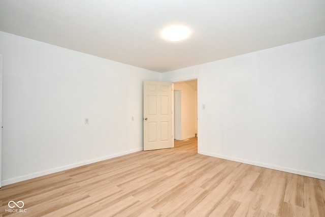 spare room featuring baseboards and light wood-style floors