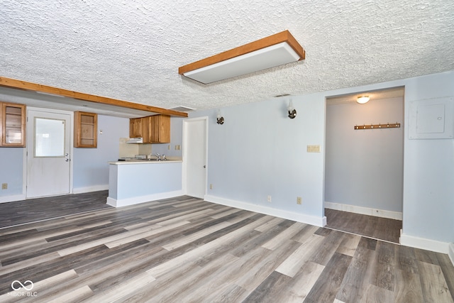 unfurnished living room featuring visible vents, baseboards, a textured ceiling, and wood finished floors