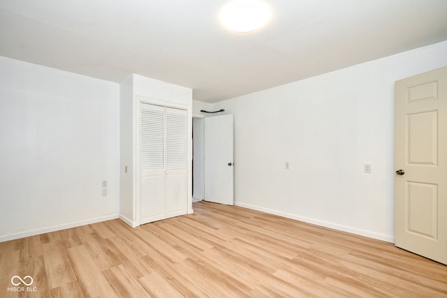 unfurnished bedroom with a closet, light wood-type flooring, and baseboards