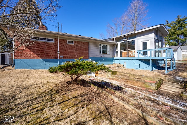 back of property with brick siding, a chimney, and stairs