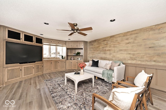 living area with light wood finished floors, a textured ceiling, and ceiling fan