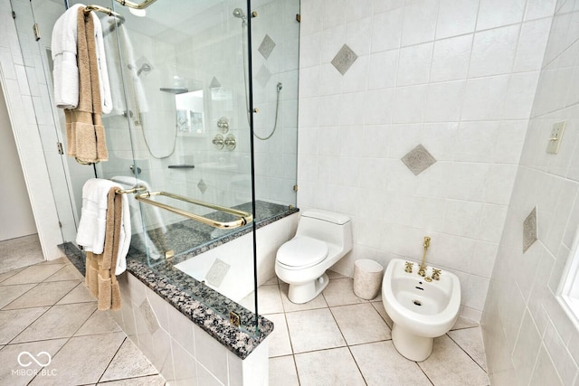 bathroom with tile patterned floors, toilet, a stall shower, a bidet, and tile walls