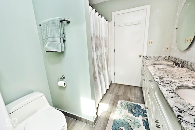 full bathroom with a sink, toilet, wood finished floors, and double vanity