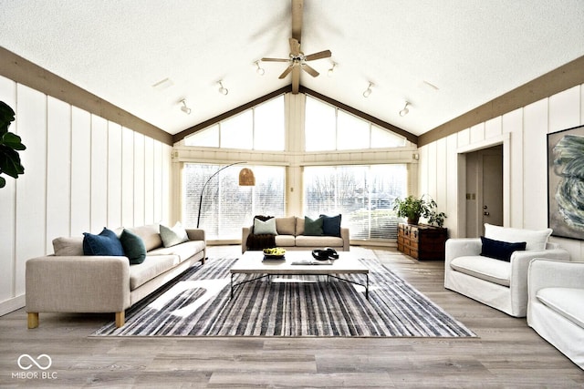 living room with beamed ceiling, high vaulted ceiling, wood finished floors, a textured ceiling, and a ceiling fan