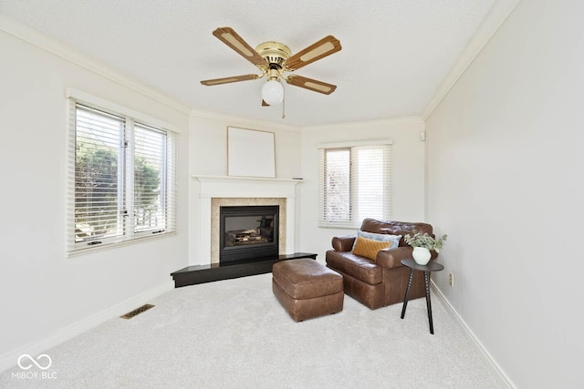 living area with carpet, visible vents, baseboards, a glass covered fireplace, and crown molding