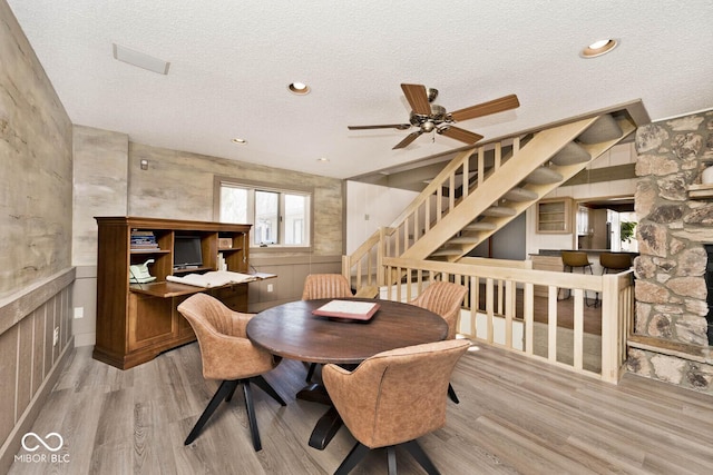 dining area featuring ceiling fan, stairway, a textured ceiling, and wood finished floors