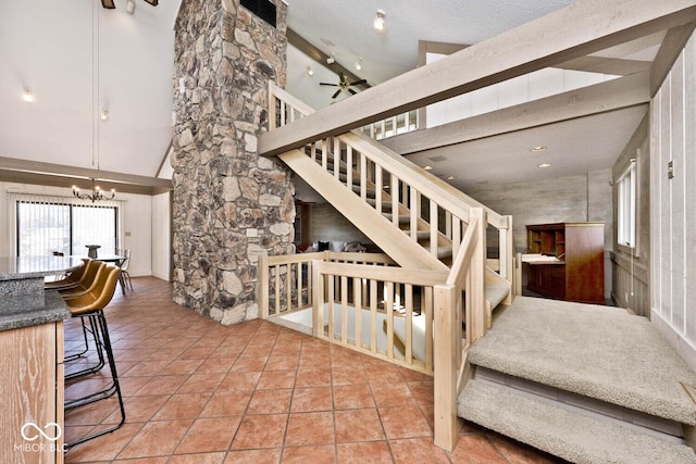 stairway featuring visible vents, ceiling fan with notable chandelier, a high ceiling, tile patterned floors, and a textured ceiling