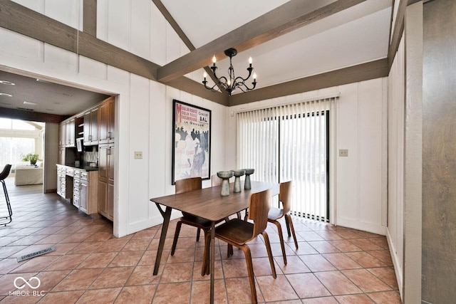 dining room featuring beamed ceiling, light tile patterned floors, a high ceiling, an inviting chandelier, and a decorative wall